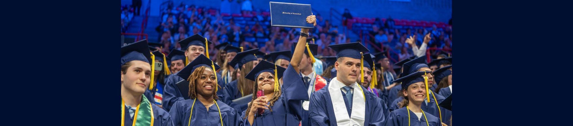 students at graduation holding up diploma