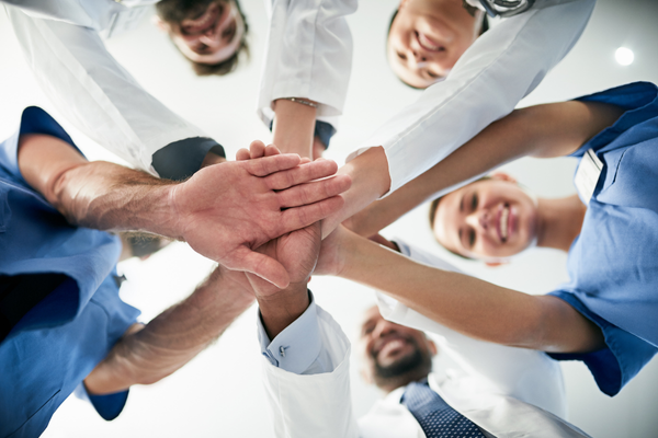health practitioners in a circle with their hands in the center